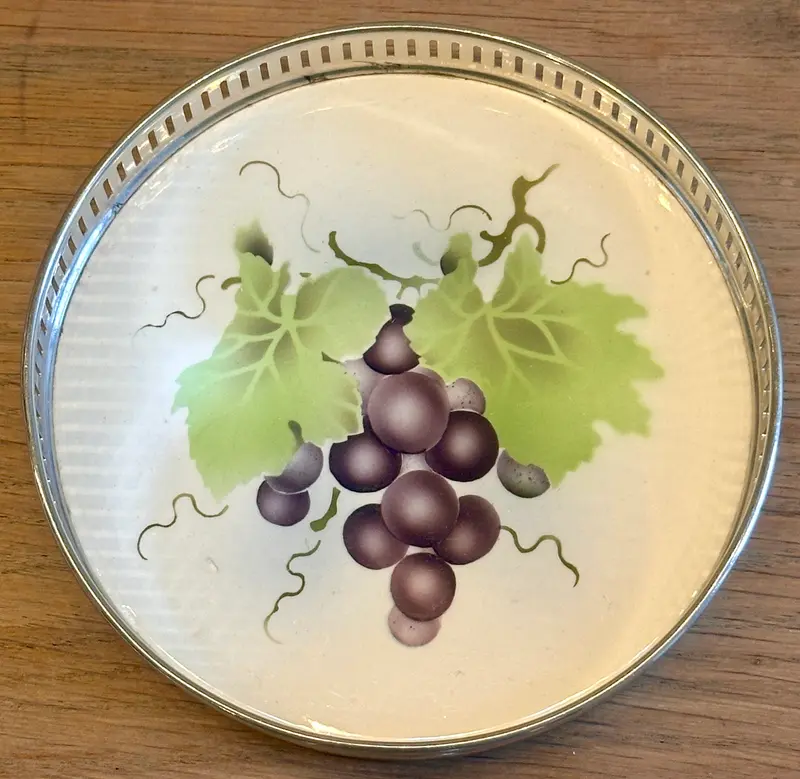 Onderzetter - voor glas of fles - ongemerkt (alleen nr. 5076 onderzijde) - opstaande rand in chroom - aardewerk plateau met décor van druiven in paars en groen